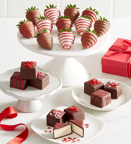 Chocolate-covered strawberries and petit fours on plates.
