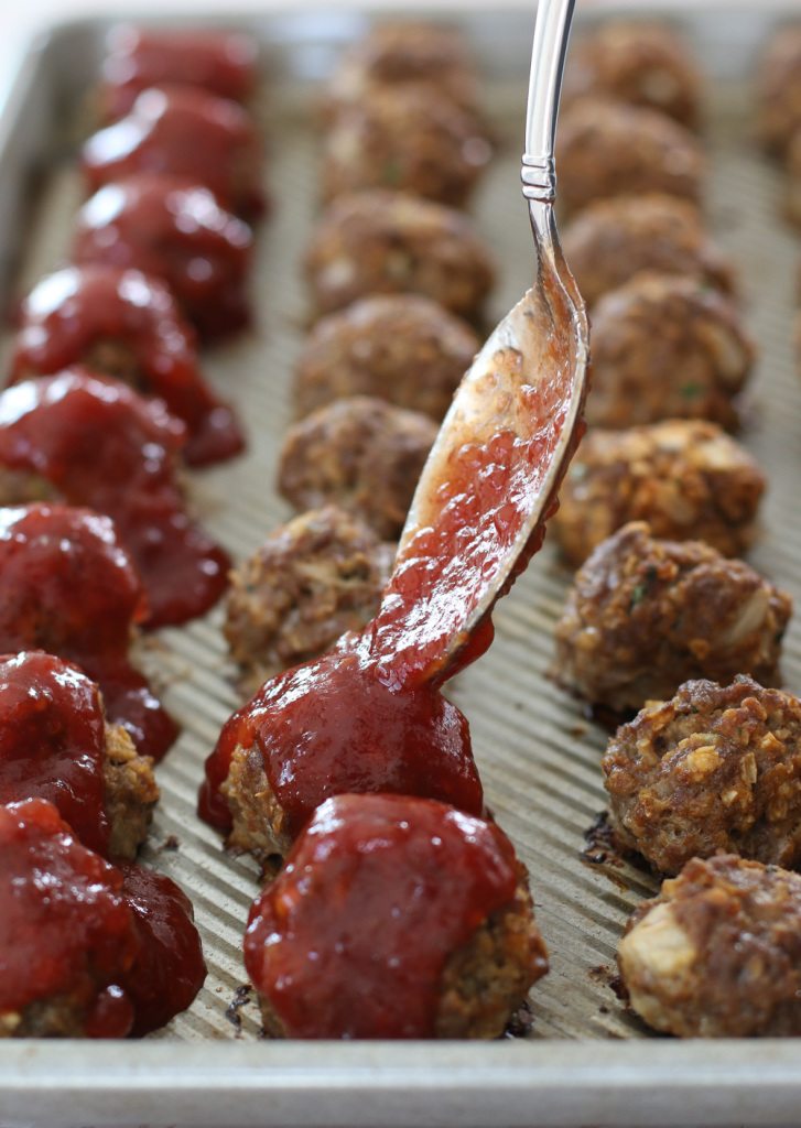 spooning cranberry sauce on meatballs