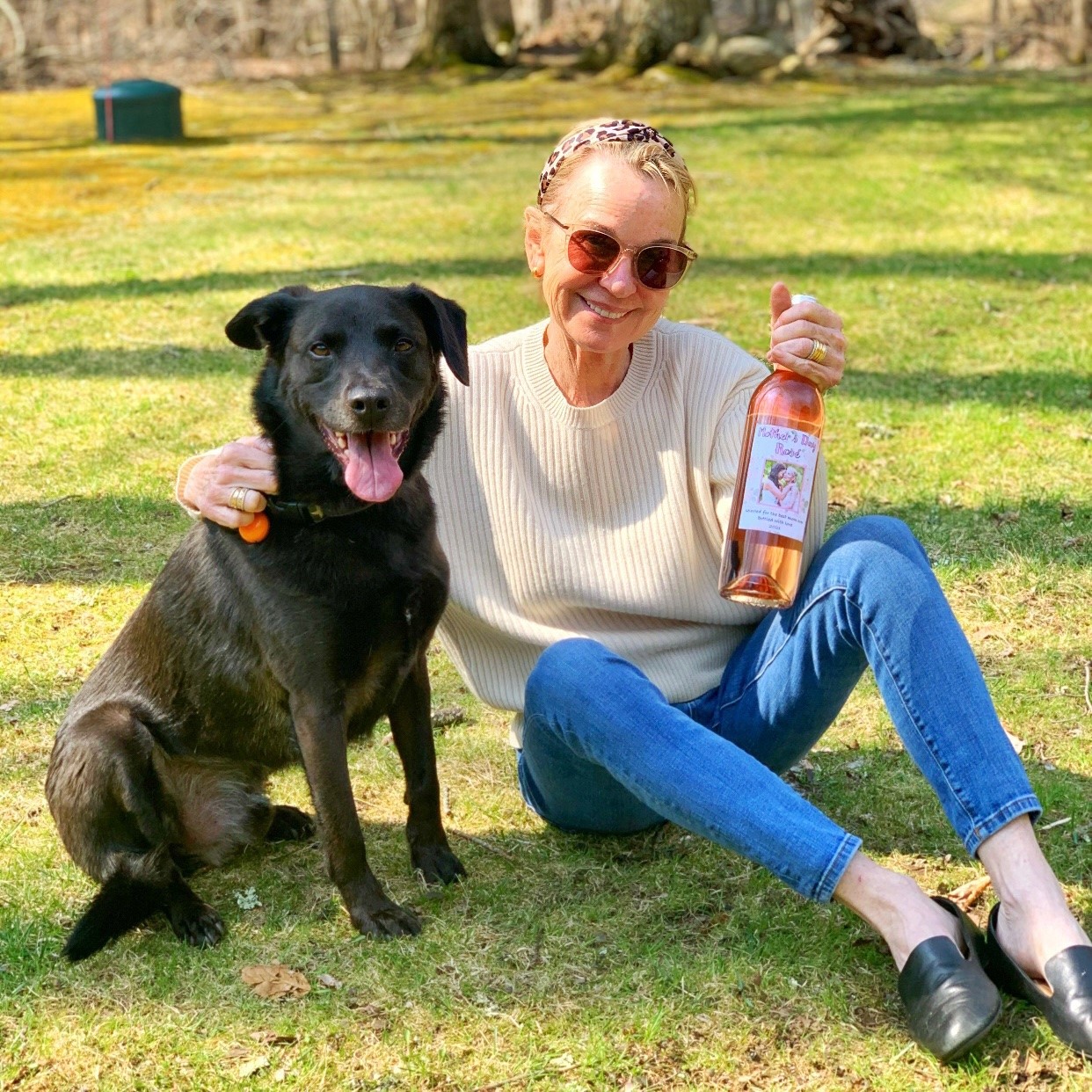 DIY mother's day gifts with a woman holding a personalized wine bottle while sitting next to a dog outside.