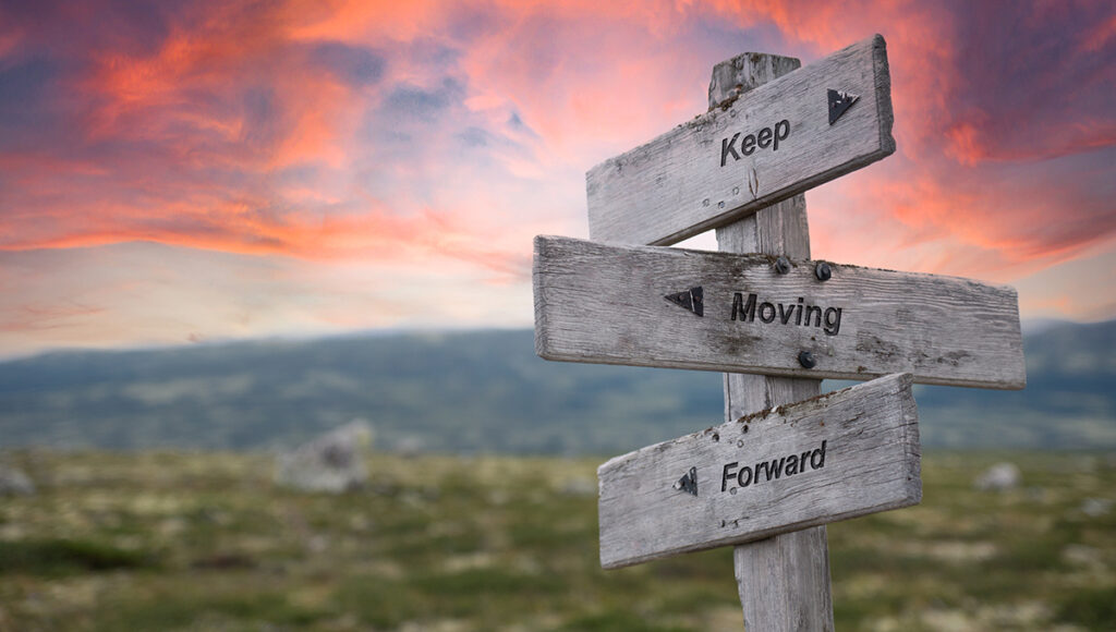 positive quotes with a sign that says keep moving forward engraved in wooden signpost outdoors