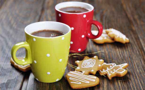 Two mugs of hot chocolate on wooden table with gingerbread cookies