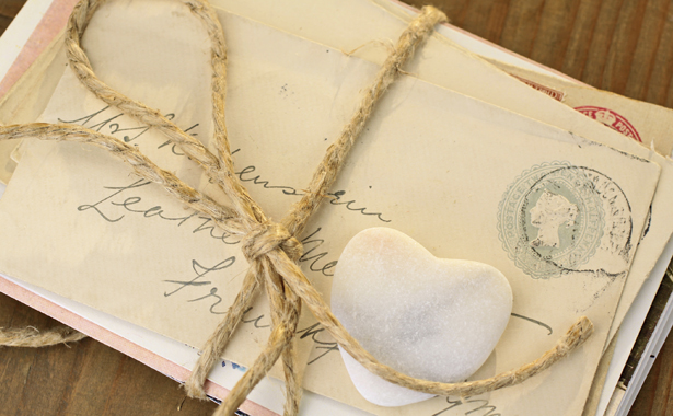Stone heart with old tied letters on wooden desk