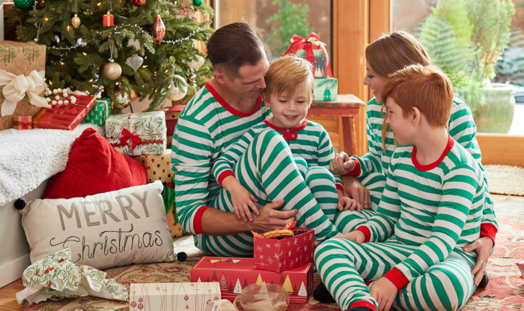 holiday spirit. A family wearing matching pajamas opening presents Christmas morning.