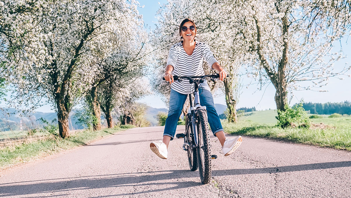 facts about spring woman riding a bicycle under apple blossom trees