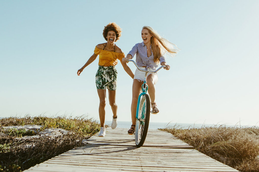 make the most of summer with two girls riding a bicycle along a boardwalk.