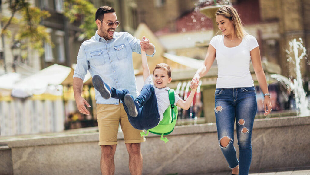 back to school family with parents swinging their son.